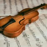 Close-up of a vintage violin resting on sheet music, highlighting the beauty of classical music.