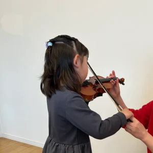 バイオリンレッスンで弓の練習をする女の子